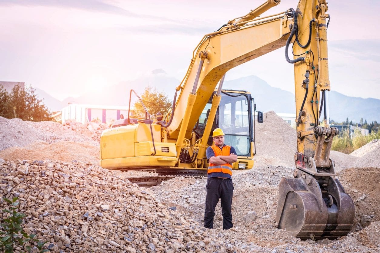 A man standing in front of a yellow construction vehicle.