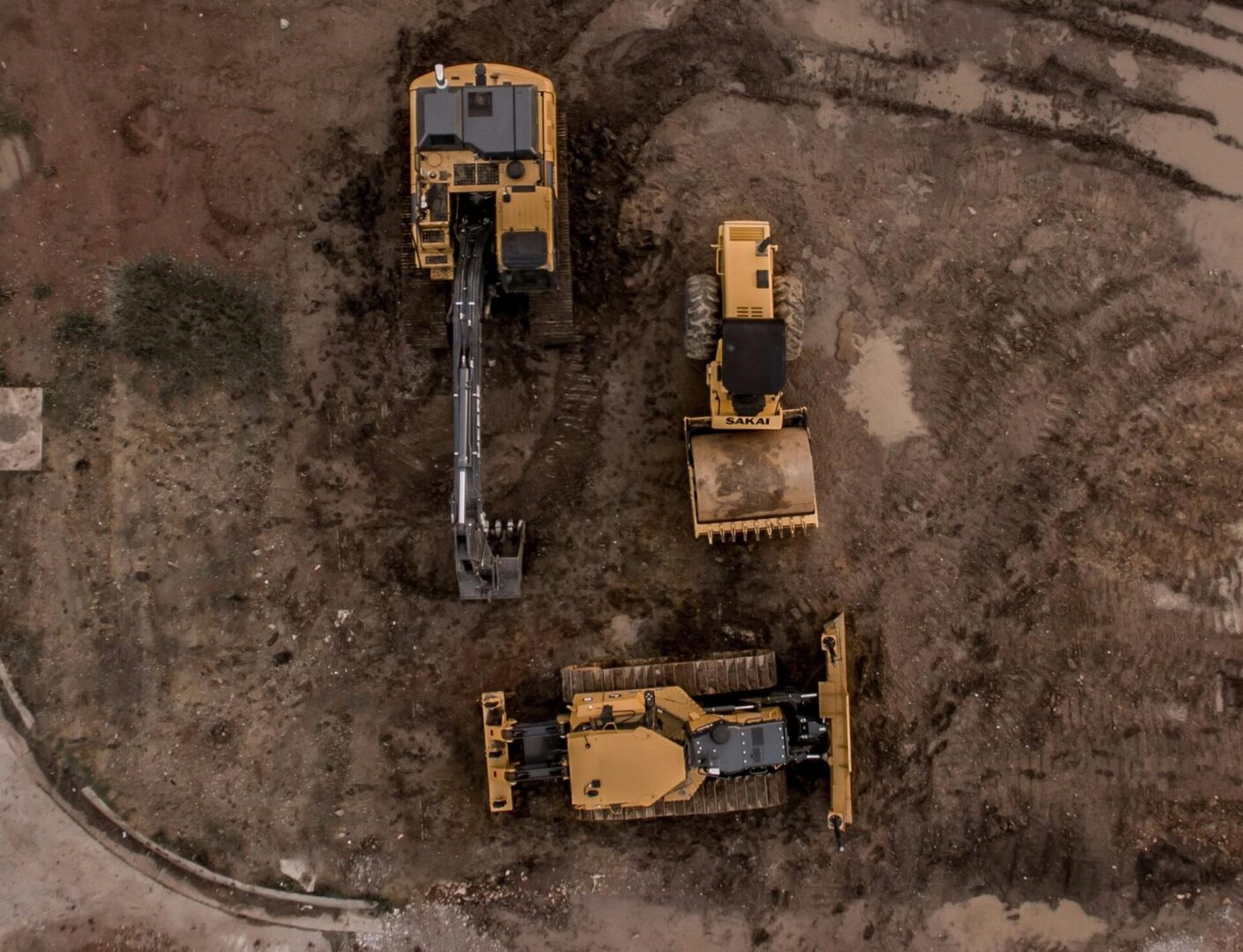 A group of construction equipment sitting on top of a dirt field.